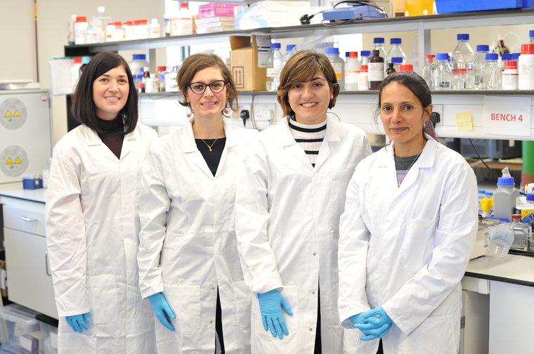 Maria Teresa and her team in their research lab in lab coats